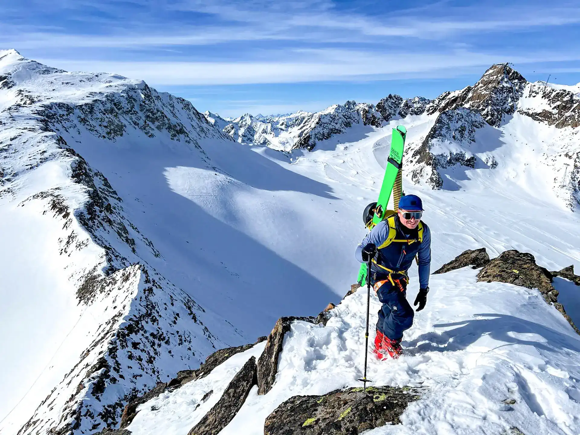 Skifahrer am Grat mit Ski am Rucksack